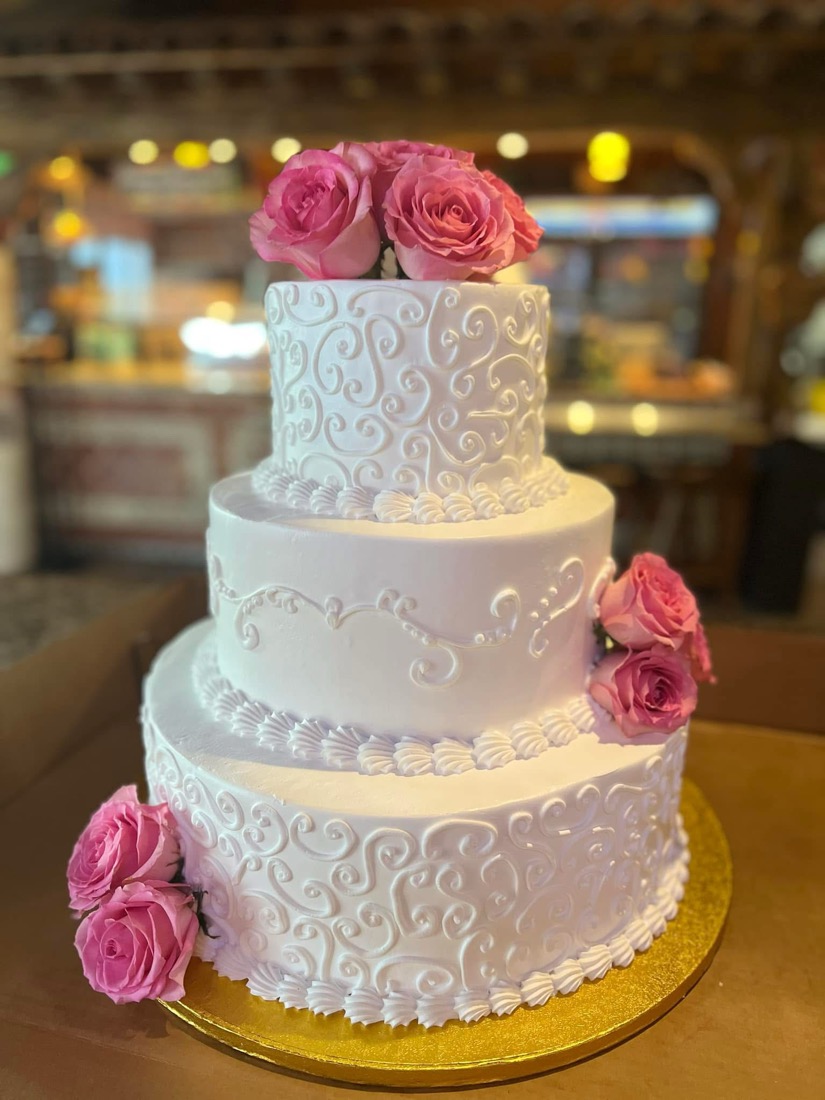 Elegant three-tier cake with piped scrollwork and roses